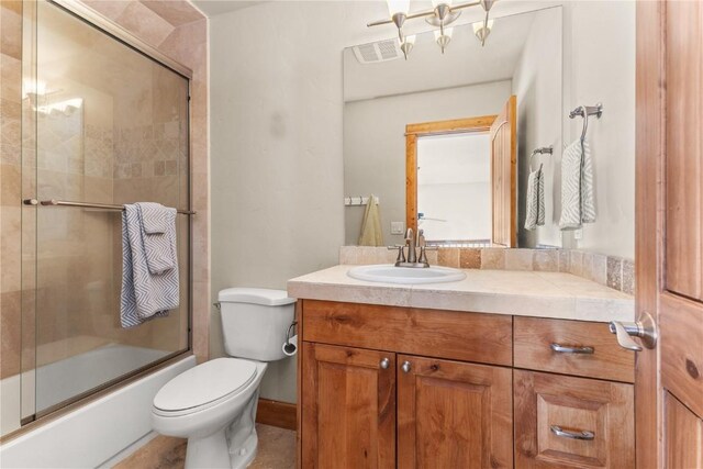 full bath featuring toilet, bath / shower combo with glass door, vanity, and visible vents