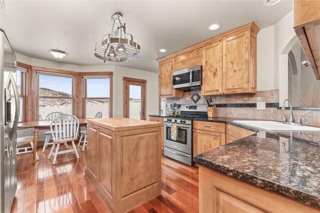 kitchen with stainless steel appliances, a sink, wood counters, light wood-type flooring, and backsplash