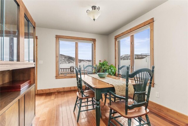 dining space featuring light wood-type flooring and baseboards