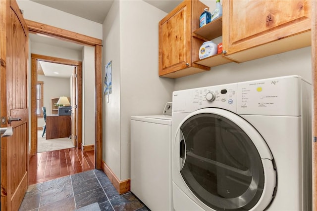 washroom with stone finish floor, cabinet space, independent washer and dryer, and baseboards