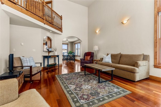 living area with hardwood / wood-style flooring, baseboards, a high ceiling, and arched walkways