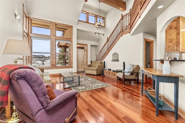 living room featuring a notable chandelier, stairway, wood-type flooring, and a healthy amount of sunlight