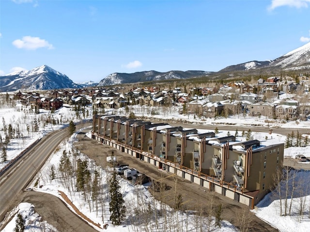 snowy aerial view with a mountain view and a residential view