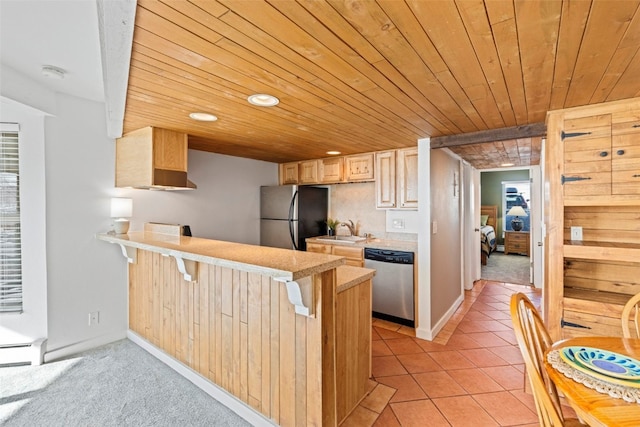 kitchen featuring a peninsula, a sink, light brown cabinetry, light countertops, and stainless steel appliances