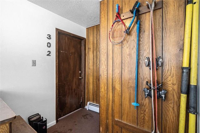 interior space featuring a baseboard heating unit, carpet floors, and a textured ceiling