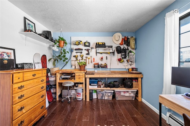 misc room featuring a baseboard heating unit, dark wood-type flooring, a textured ceiling, and a workshop area