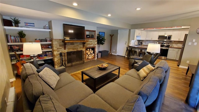 living room featuring hardwood / wood-style flooring, a stone fireplace, and sink