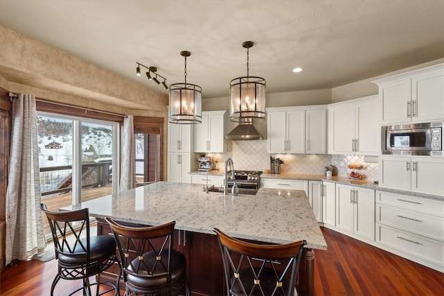 kitchen featuring decorative backsplash, stainless steel microwave, dark wood-type flooring, and a sink