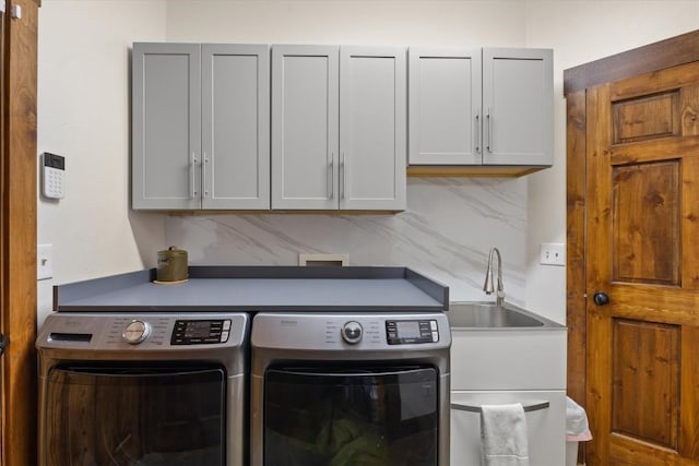 laundry room with cabinet space, separate washer and dryer, and a sink