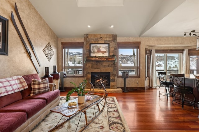 living area featuring lofted ceiling, plenty of natural light, a fireplace, and wood finished floors