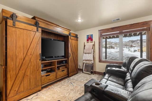 living room featuring a barn door, visible vents, and baseboards