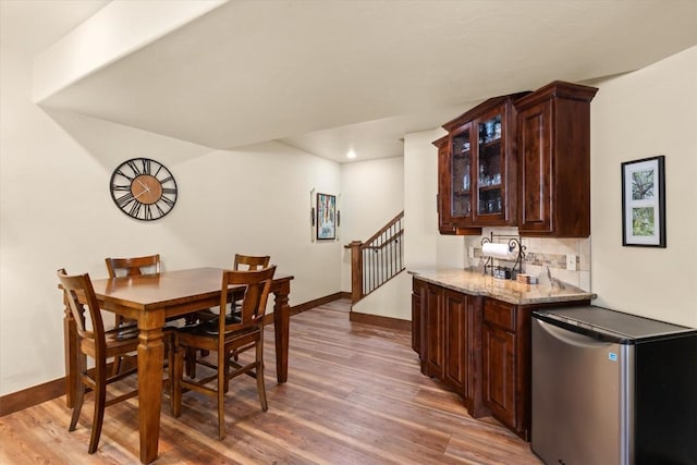 dining area with light wood-type flooring, stairway, baseboards, and recessed lighting