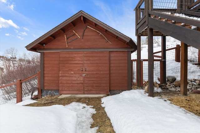 snow covered structure featuring a storage shed, fence, and an outdoor structure