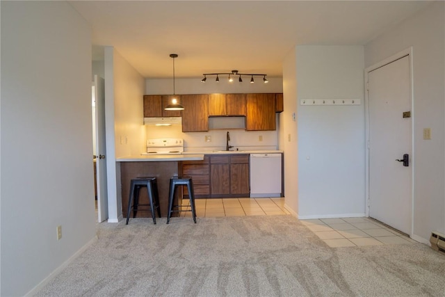 kitchen with light colored carpet, sink, decorative light fixtures, dishwasher, and a breakfast bar area