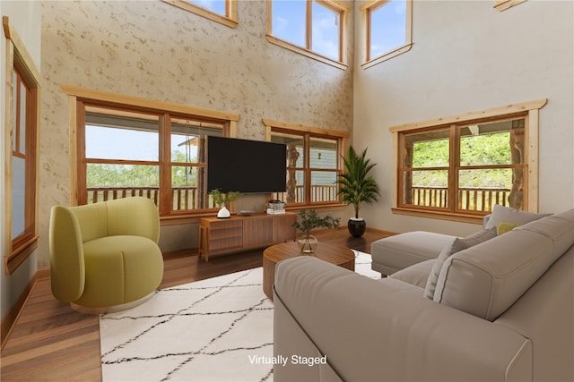 living room with baseboards, plenty of natural light, a high ceiling, and wood finished floors