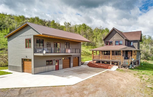 view of front of property with a balcony, an attached garage, covered porch, and driveway