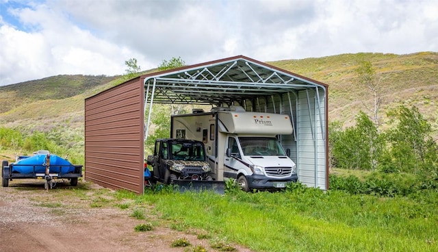 view of outbuilding with a mountain view, a detached carport, and dirt driveway