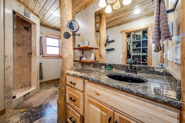 full bath featuring a tile shower, wood ceiling, vanity, and baseboards