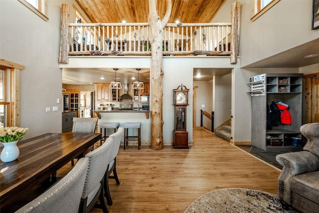 dining space with stairway, wooden ceiling, light wood-style floors, and a towering ceiling