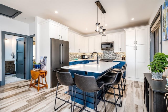 kitchen with a kitchen bar, tasteful backsplash, white cabinetry, appliances with stainless steel finishes, and light countertops