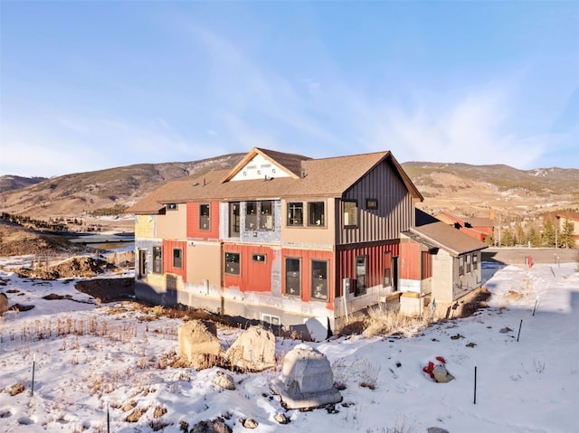 snow covered rear of property featuring a mountain view