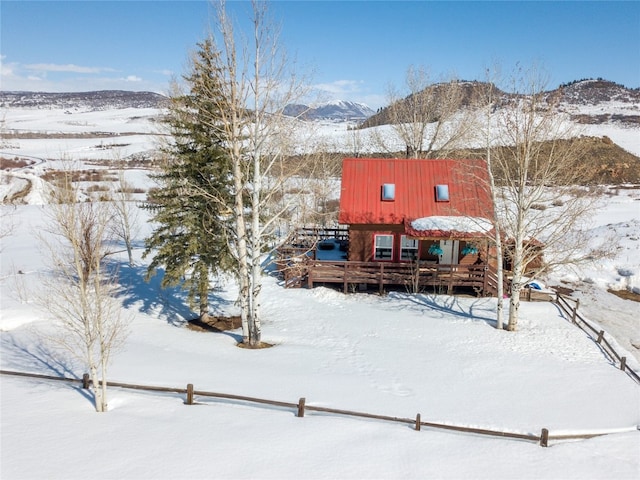 snow covered property featuring metal roof and a deck with mountain view