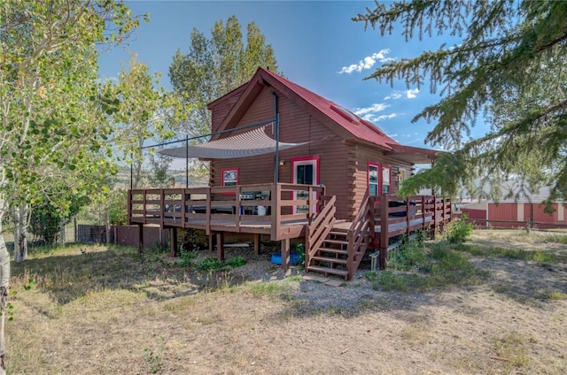 back of house featuring log siding, metal roof, a deck, and fence