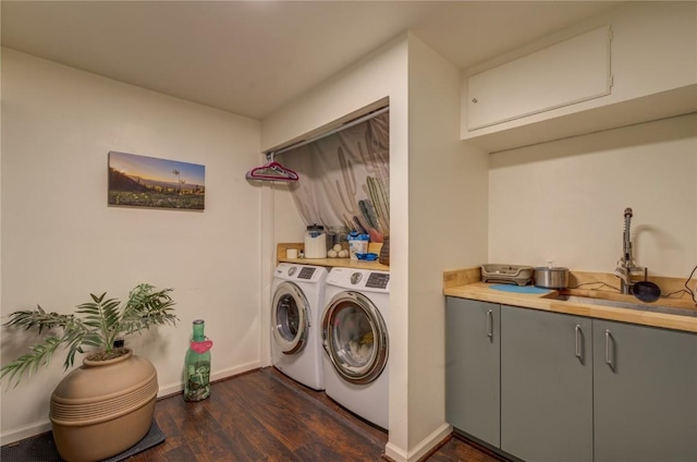 washroom with baseboards, cabinet space, dark wood-style flooring, a sink, and washing machine and dryer