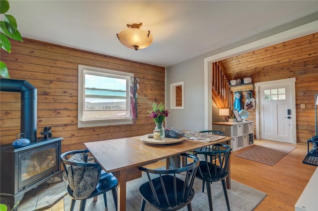 dining space with a wealth of natural light, wooden walls, and light wood-style floors