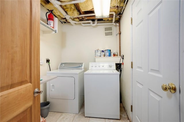 laundry area featuring washing machine and dryer and light tile patterned floors