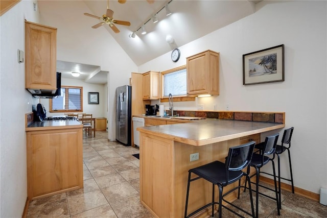 kitchen featuring stainless steel fridge, a kitchen breakfast bar, kitchen peninsula, and plenty of natural light