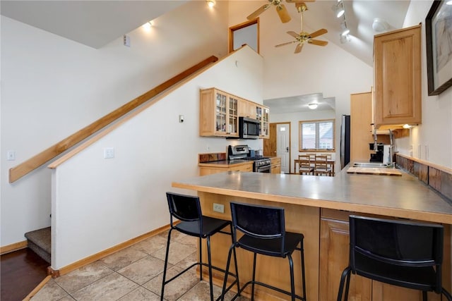 kitchen featuring appliances with stainless steel finishes, a breakfast bar, sink, light tile patterned floors, and kitchen peninsula