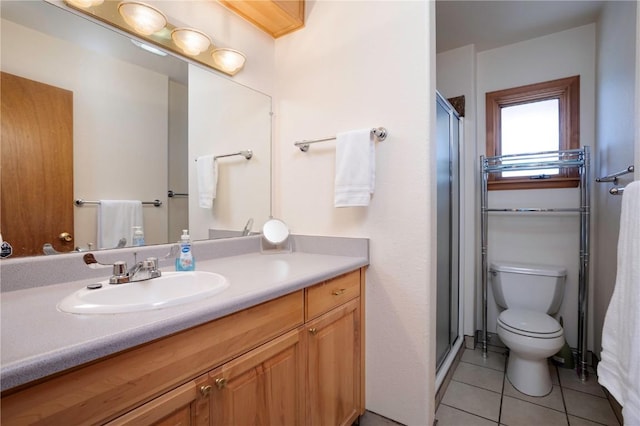 bathroom featuring tile patterned floors, toilet, a shower with door, and vanity