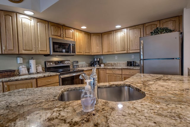 kitchen featuring appliances with stainless steel finishes, light stone countertops, and sink