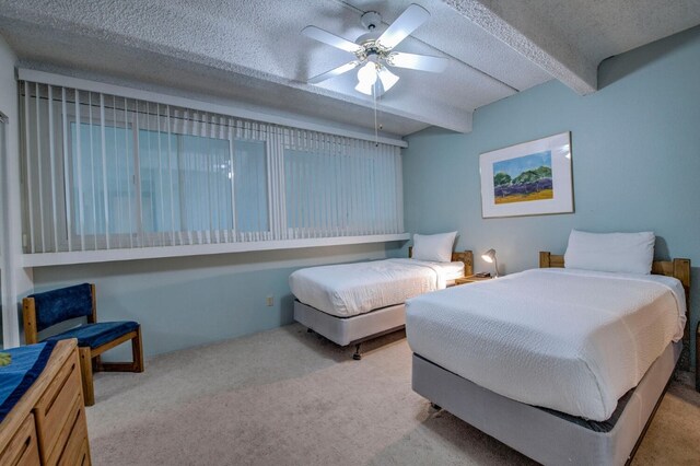 carpeted bedroom with ceiling fan, a textured ceiling, and beam ceiling