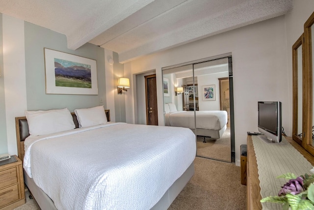 carpeted bedroom featuring a textured ceiling, a closet, and beamed ceiling