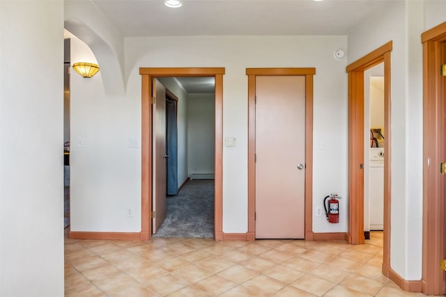 hall featuring light colored carpet, washer / clothes dryer, and baseboard heating