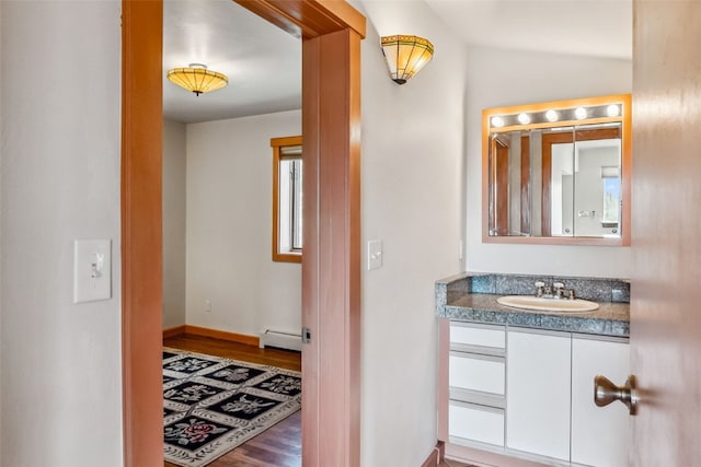 bathroom with hardwood / wood-style flooring, vanity, and a baseboard heating unit