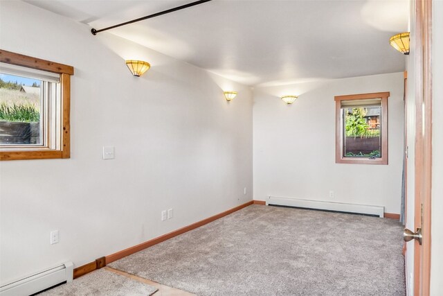 carpeted empty room with a baseboard heating unit