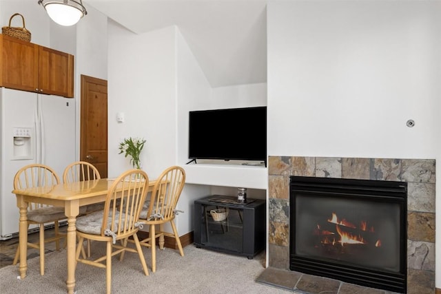 dining area with light carpet and a tile fireplace