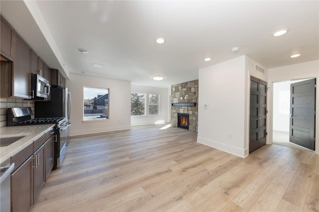 kitchen featuring visible vents, light wood-style floors, appliances with stainless steel finishes, open floor plan, and backsplash