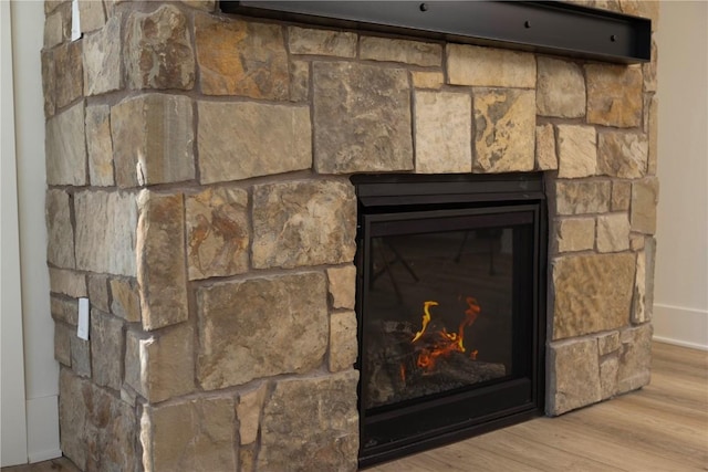 room details with a stone fireplace and wood finished floors