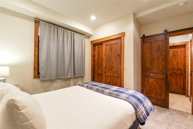 bedroom featuring a barn door and light colored carpet