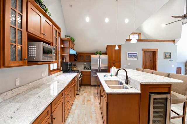 kitchen with hanging light fixtures, a breakfast bar area, an island with sink, stainless steel appliances, and beverage cooler