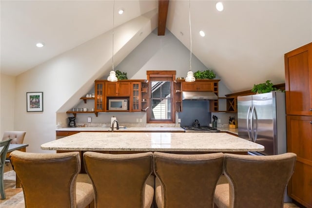 kitchen featuring light stone countertops, appliances with stainless steel finishes, lofted ceiling with beams, and decorative light fixtures