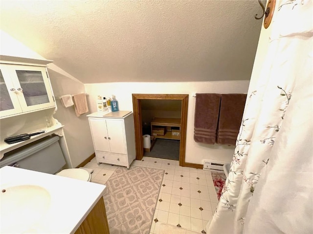 bathroom featuring toilet, a textured ceiling, and vaulted ceiling