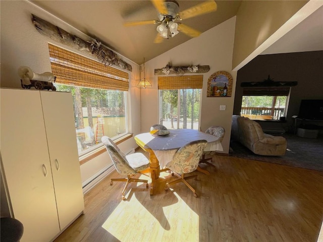 dining room featuring ceiling fan, light hardwood / wood-style floors, a baseboard heating unit, and vaulted ceiling