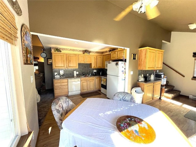 kitchen featuring light brown cabinets, white appliances, dark wood-type flooring, decorative backsplash, and a towering ceiling