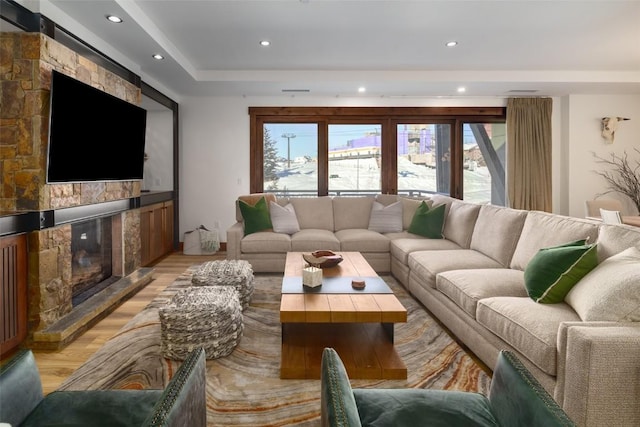 living room with a stone fireplace and light hardwood / wood-style flooring