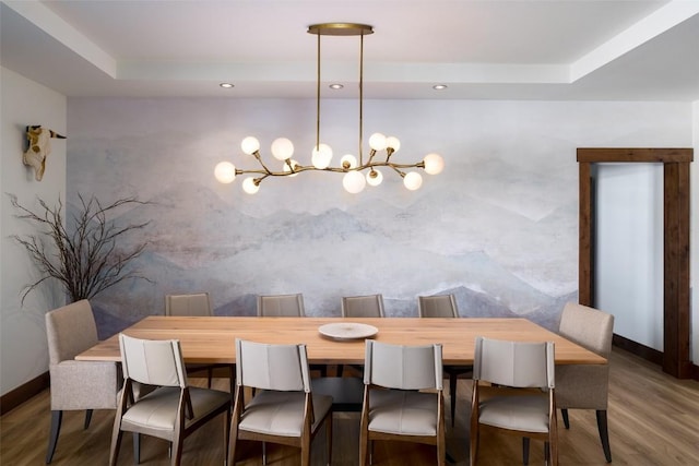 dining room featuring a raised ceiling, wood-type flooring, and an inviting chandelier